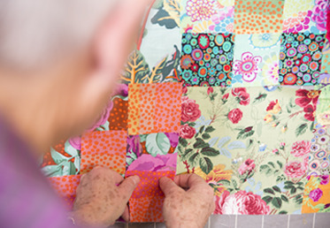 Kaffe Fassett mocks up a layout on his trademark design wall, working with prints in different scales to achieve a version of his classic pattern in a leafy, misty spring mood.