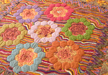 Kaffe Fassett and Liza work together to create a masterful medallion quilt in rich, warm tones. The quilt begins with a stunning medallion center that is comprised of English paper-pieced hexagon rings and hand-appliqued fussy-cut fabrics. 