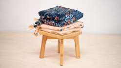 Two fleece blankets on a wooden stool.