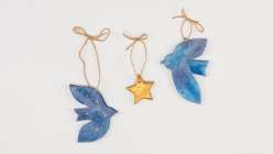 Three salt-dough ornaments hand-painted and tied with twine, including two bluebirds and one gold star.