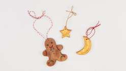 Three salt-dough ornaments tied with twine, including a gingerbread man, a star, and a moon.