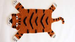 An ochre-colored crocheted rug in the shape of a tiger, made in Twinkie Chan's Crochet a Wild Animal Rug class on Creativebug