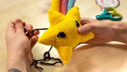 A pair of hands assembling a stuffed crocheted star from Vincent Green-Hite's Crochet an Amigurumi Shooting Star Creativebug class
