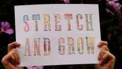 Two hands holding a poster of hand-cut letters reading Stretch and Grow from Dawn M. Cardona's Craft Yourself a Love Note Creativebug class