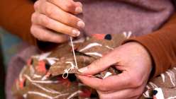 A closeup image of Cal Patch's hands sewing a T-shirt from her Creativebug class