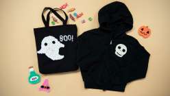 A black tote bag adorned with a crocheted ghost and a black sweatshirt with a crocheted skull from Twinkie Chan's Crochet Halloween Appliques class on Creativebug