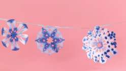 Blue and white paper snowflakes made in Mia Semingson's Make Shibori-Inspired Paper Snowflakes class on Creativebug