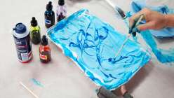 Hands marbling a tray of shaving cream in Bel Mills's Love Note Zine Using Marbled Papers class on Creativebug
