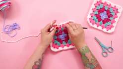 A pair of hands crocheting a granny square from Twinkie Chan's Crochet a Granny Square class on Creativebug, produced in conjunction with Joann Stores.