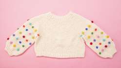 A cream-colored crocheted sweater with brightly colored bobbles made in Twinkie Chan's Design and Crochet a Top-Down Bobble Sweater class on Creativebug.