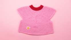 A cropped pink sweater with a red neckband made in Twinkie Chan's Design and Crochet a Top-Down Bobble Sweater class on Creativebug.