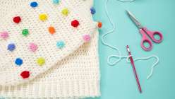A cream-colored crocheted sweater with brightly colored bobbles made in Twinkie Chan's Design and Crochet a Top-Down Bobble Sweater class on Creativebug.