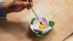 A white peony flower being painted by Cindy Willingham's in her Make a Peony with Air-Dry Clay class on Creativebug.