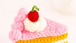 A crochet cake slice topped with yarn whipped cream and a cherry from Twinkie Chan's Crochet Cakery Daily Practice class on Creativebug