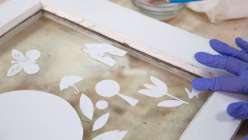Dawn M. Cardona in the process of gluing down decorative shapes of cut paper for her Cut-Paper Silhouettes for Home Decor class on Creativebug.