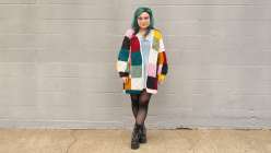 Twinkie Chan wearing a multicolored crochet sweater with yellow ribbed cuffs that she made in her Crochet a Granny Square Cardigan class on Creativebug. 