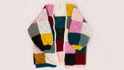 A multicolored crochet sweater with yellow ribbed cuffs made by Twinkie Chan in her Crochet a Granny Square Cardigan class on Creativebug. 