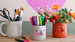 A grey and orange vase, both with pink cheeks and skeptical expressions, made by Cindy Willingham in her Hand-Built Vases with Air-Dry Clay class on Creativebug.