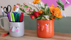 A grey and orange vase, both with pink cheeks and skeptical expressions, made by Cindy Willingham in her Hand-Built Vases with Air-Dry Clay class on Creativebug.