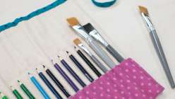 A purple pencil roll full of a rainbow of colored pencils, made in Faith Hale's Sew a Paint Brush and Pencil Roll class on Creativebug.