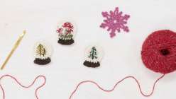 Three crocheted snow globes and a crocheted snowflake made by Twinkie Chan in her Holiday Crochet Applique class on Creativebug