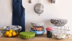A selection of kitchen implements and eight bowls and jars of various sizes covered with fabric toppers made in the Creativebug class Sew Reusable Bowl Covers.