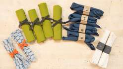 A selection of colorful napkins tied with leather napkin ring made in the Make Leather Napkin Rings class on Creativebug