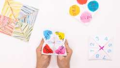 A pair of hands holding a paper fortune teller made by Courtney Cerruti in her class on Creativebug.