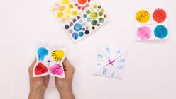 A pair of hands holding a paper fortune teller made by Courtney Cerruti in her class on Creativebug.