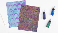 An example each of a marbled piece of paper and an overmarbled piece of paper from Mercedez Rex's Overmarbling On Paper class on Creativebug.