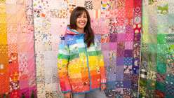 Taiga from House of Taiga modeling a vibrant, handcrafted jacket made in her Rainbow Gradient Quilted Coat class on Creativebug.